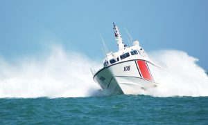 U.S. Coast Guard patrol boat speeding through ocean waves, symbolizing national security and enforcement of mandatory cybersecurity regulations.
