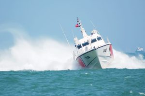 U.S. Coast Guard patrol boat speeding through ocean waves, symbolizing national security and enforcement of mandatory cybersecurity regulations.